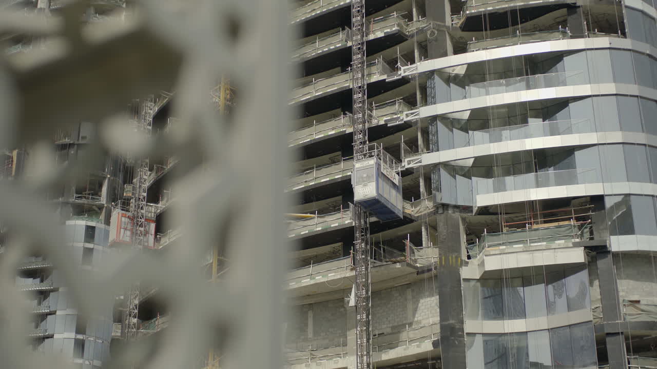 una observación de un rascacielos en construcción en dubái, emiratos árabes unidos, muestra una grúa levantando trabajadores en la cima de la estructura altísima, que generalmente alcanza una altura de 180 metros al completarse.