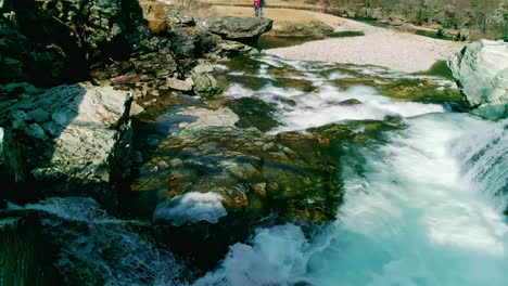 Dron-Aéreo-Vuela-Bajo-Cerca-De-La-Cascada,-Paisaje-De-Piedra-De-La-Cascada-Pareja-Mirando,-Entorno-Natural