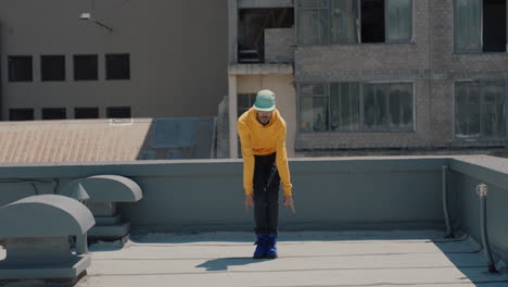 dancing man hip hop dancer performing freestyle dance moves on rooftop in city wearing yellow hoodie