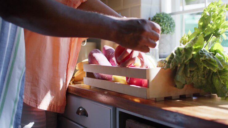 Grocery crate arriving, couple sorting and inspecting produce for storage at sunlit counter