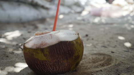 bebida de agua de coco natural fresca en la playa de arena con pajita de plástico en puerto escondido, méxico