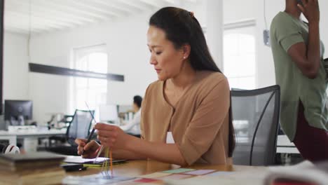 Feliz-Empresaria-Asiática-Tomando-Notas-En-La-Oficina