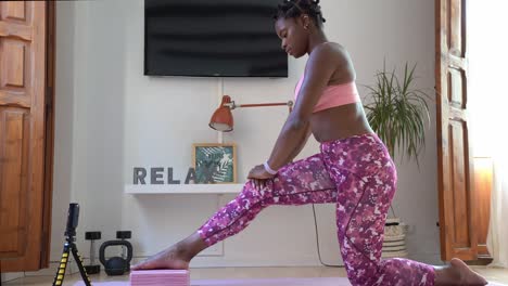 black woman practicing yoga in crescent lunge pose during online class