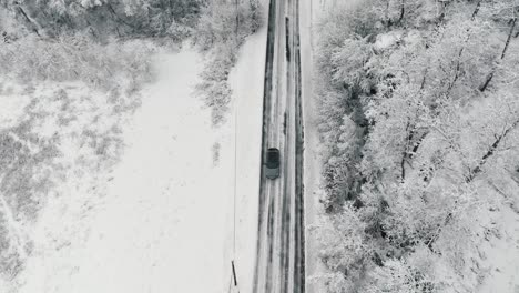 Drohnenaufnahmen-Von-Einem-Auto,-Das-Auf-Einer-Winterlichen-Waldstraße-Fährt