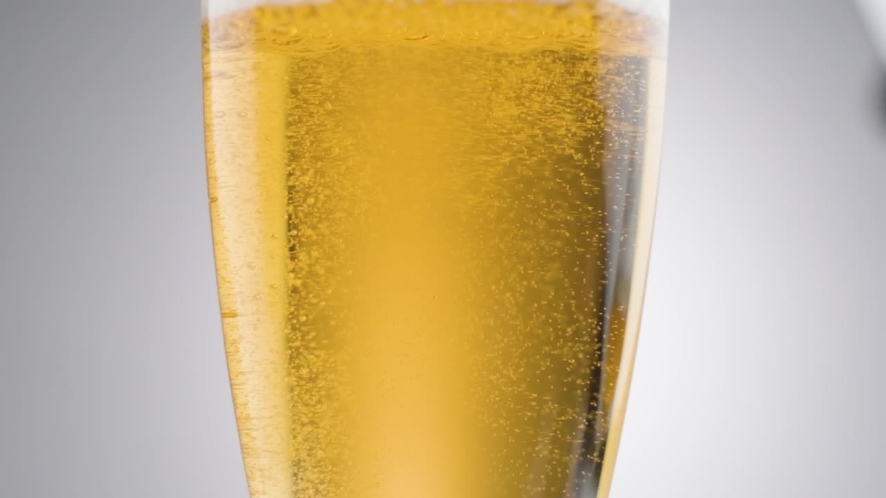 Slow motion shot alcoholic luxury drink, golden bubbles moving up, white background