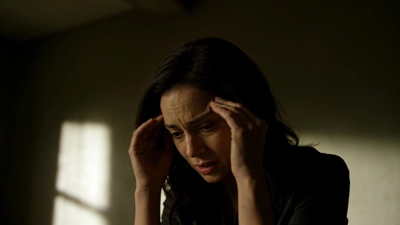 Reacting to rising headache, woman pressing temples and bowing head in small room, window sunlight