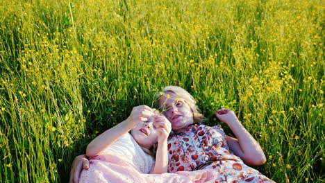 mom and 6 year old daughter are talking together in a tall grass