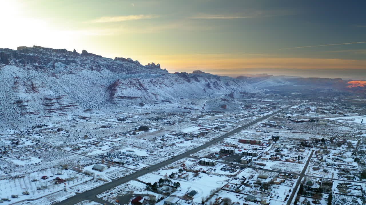 Aerial view of a snow-covered town in a desert mountain landscape at sunset