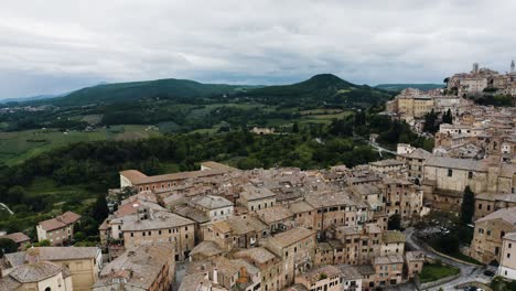 Swooping-aerial-view-of-Montepulciano,-Tuscany-overlooking-Italy's-green-countryside