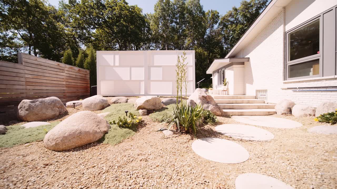 Ingresso in un moderno giardino con blocchi frangivento ispirato alla California, con una porta rossa sul lato di una casa di lusso