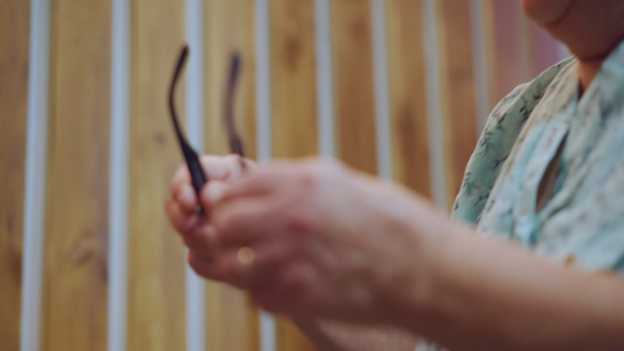 Anziana signora riflessiva. Nonna bianca in un momento di riflessione. Donna anziana dolcemente concentrata con un'atmosfera nostalgica. Un'anziana signora che allunga delicatamente la mano verso gli occhiali in un tranquillo contesto pomeridiano.