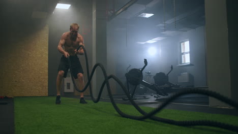 Male-athlete-working-out-with-ropes-in-old-building.-Athlete-man-in-training-with-ropes-near-mirror.-Battle-Rope