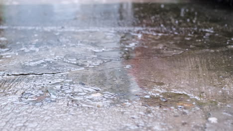 lluvia cayendo sobre asfalto con charco. de cerca