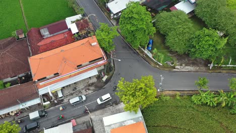 Antena-De-Arriba-Hacia-Abajo-Del-Tráfico-Acercándose-A-Una-Bifurcación-En-La-Carretera-En-Bali,-Indonesia