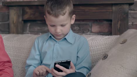 blond haired child plays games on black smartphone in room