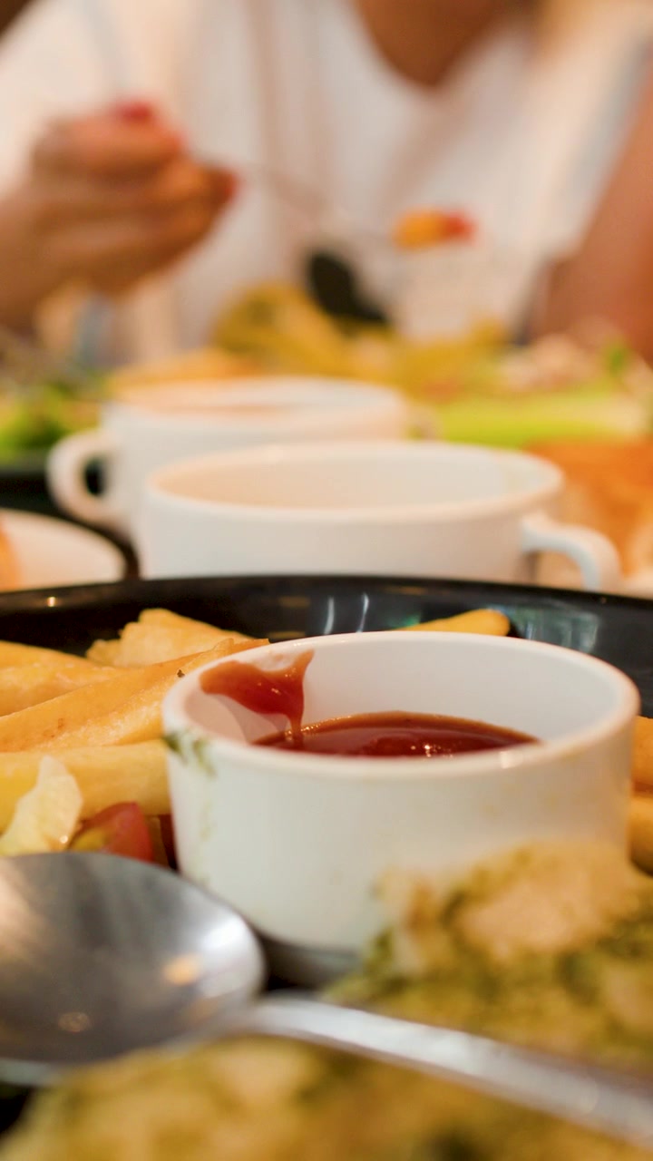 Un primo piano di cibo da ristorante mentre una persona mangia un'insalata sullo sfondo.