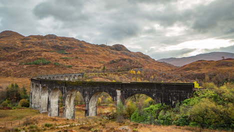 scotland, scottish highlands glenfinnan rail viaduct time lapse in autumn, waiting for a train on the railway with clouds scudding over landscape