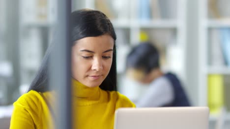 Retrato-De-Una-Linda-Chica-Sonriendo-Y-Mirando-La-Cámara-Mientras-Se-Sienta-Y-Trabaja-Con-La-Computadora-En-La-Oficina