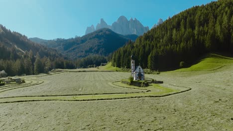 ripresa aerea con drone delle dolomiti nella chiesa di san giovanni a ranui con la foresta e le alpi sullo sfondo, italia, dolomiti