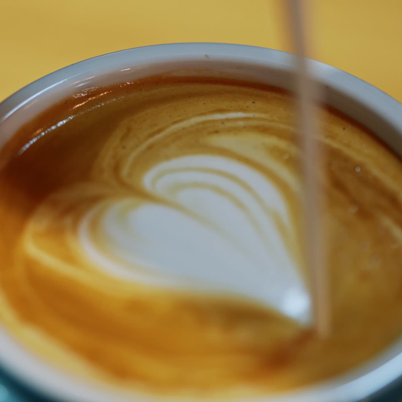 Barista making of cafe latte art. Heart shape on coffee in a cup. Making latte by pouring milk slowly into a blue cup. Close-up.