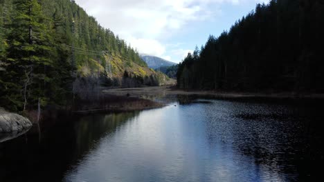 Impresionante-Dron-Dolly-Disparado-Sobre-El-Lago-Con-La-Montaña-Al-Fondo-Y-El-Reflejo-Del-Bosque-En-El-Agua