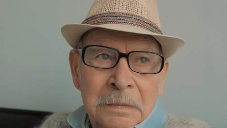 portrait of old serious male with gray mustache, hat, glasses and cane