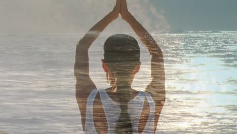 woman doing yoga beside the ocean