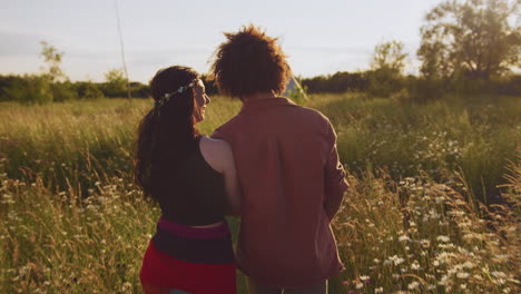 young romantic couple walking through field towards teepee on summer camping vacation