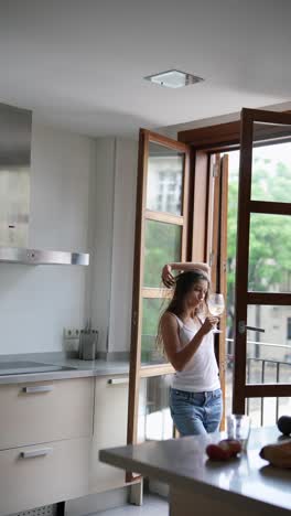 woman dancing in a kitchen with a glass of wine