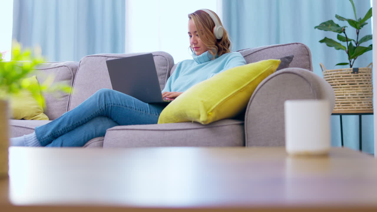 Laptop, couch and headphones of asian woman