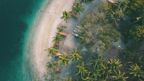 Ein-Abwärtsschuss,-Der-über-Einen-Strand-Mit-Einigen-Bungalows-Und-Palmen-Fliegt