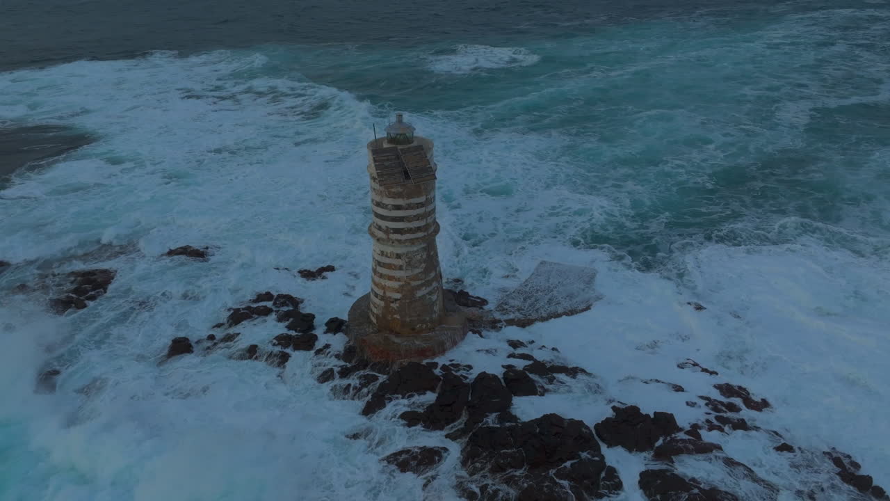 маяк мангиабарче, сардиния: орбитальный воздушный вид красивого маяка и разбивающихся волн