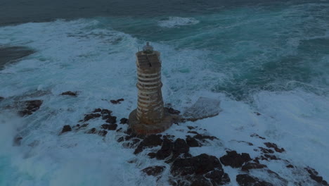 mangiabarche lighthouse, sardinia: orbital aerial view of the beautiful lighthouse and with the crashing waves