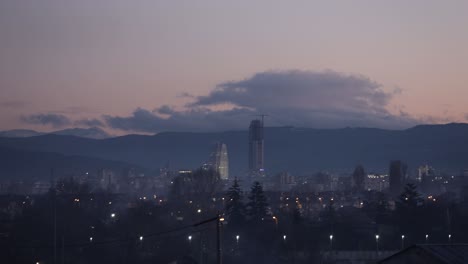 lapso de tiempo de un horizonte de la ciudad con una montaña detrás de él, al anochecer
