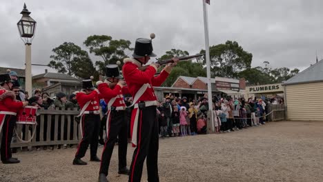 soldiers in red coats firing rifles for crowd