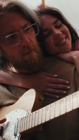 couple playing guitar at home