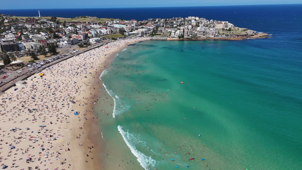Drone shot of Bondi Beach, showcasing people swimming, sunbathing, and relaxing along the coastline. Revealing aerial view, NSW, Australia