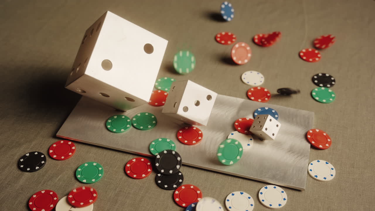 Inquadratura media di una scultura di dadi grigi e fiches da poker colorate che cadono su un tavolo grigio, inquadratura statica.