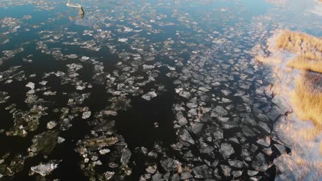 aerial scene of frozen lake in early spring, landscape covered in broken ice from winter