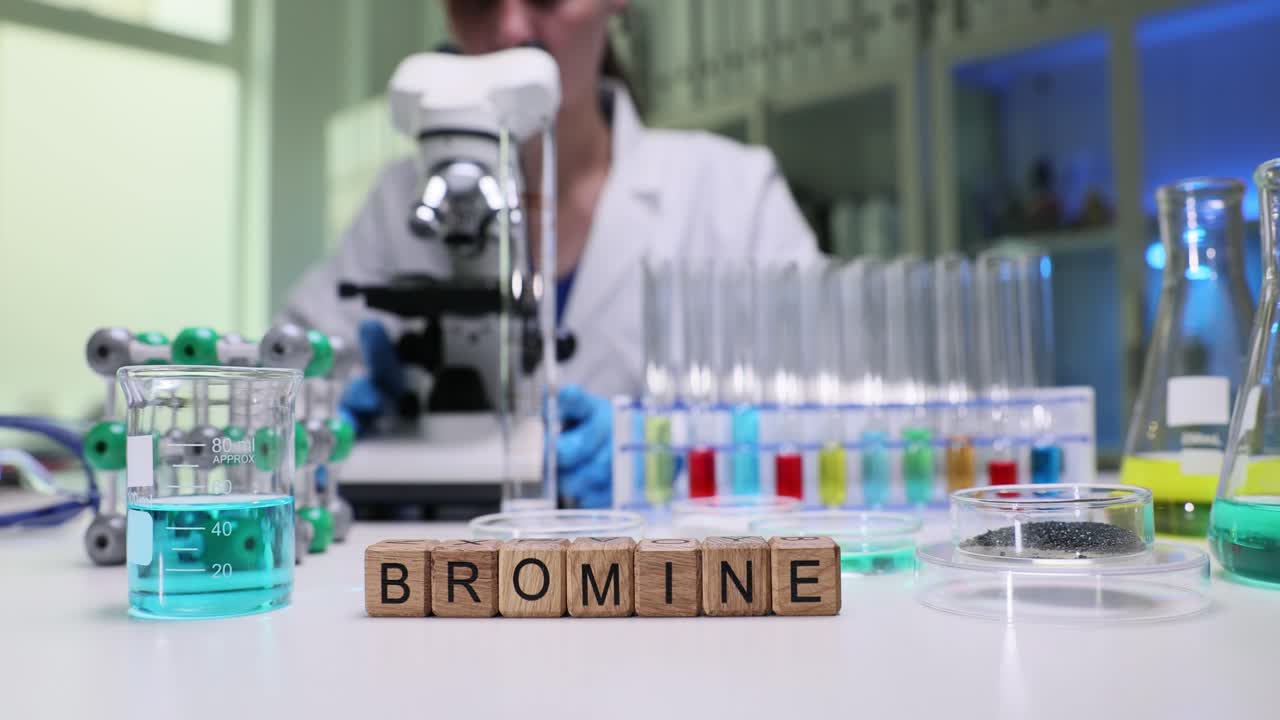 Holzklötze buchstabieren Brom, während ein Laborforscher Proben vorbereitet