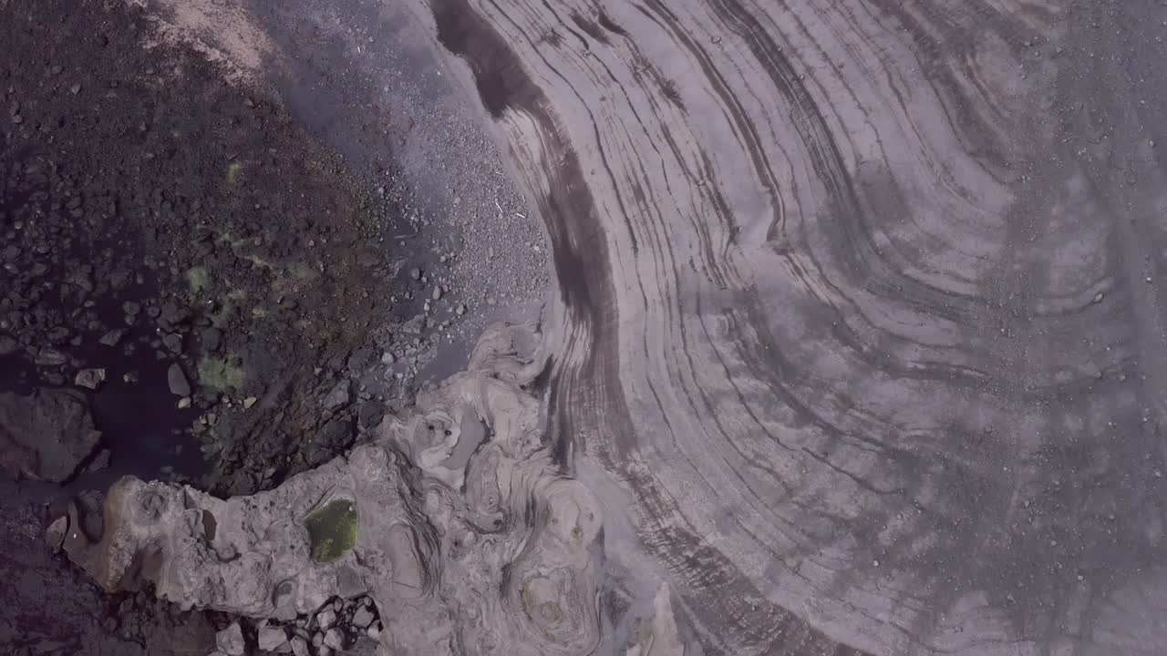 Volcanic lines on coast of Stórhöfði peninsula of remote island Heimaey, aerial