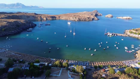 Playa-De-Agios-Pavlos-En-Rodas,-Grecia-Con-La-Acrópolis-De-Lindos,-Casas-Y-El-Mar-Mediterráneo-Durante-El-Día-Filmado-Con-El-Drone