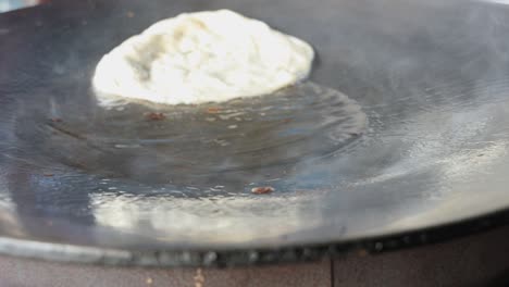 Street-food-vendor-is-pan-frying-plain-paratha-roti,-a-kind-of-Indian-flatbread,-in-smoking-hot-oil-until-crispy-on-the-outside