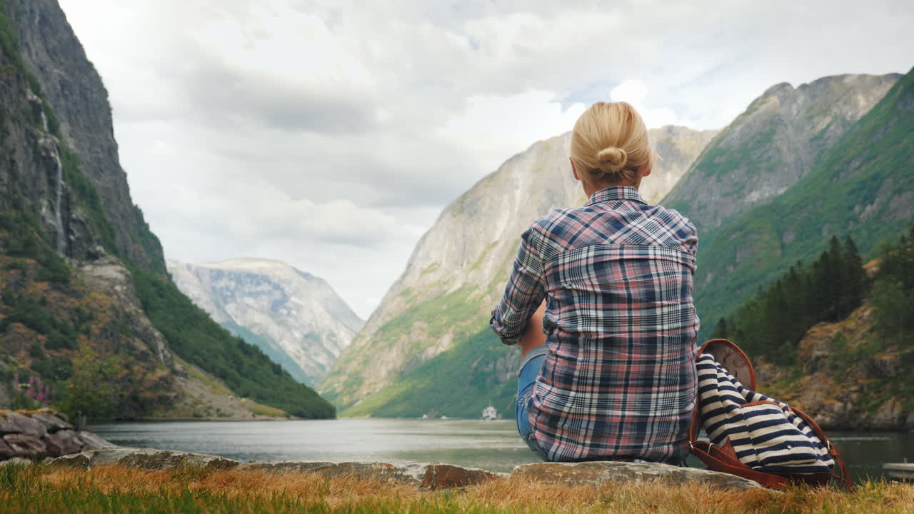 turista con mochila y bandera de noruega admira el grandioso turismo de fiordos en escandinavia concepto 4k v