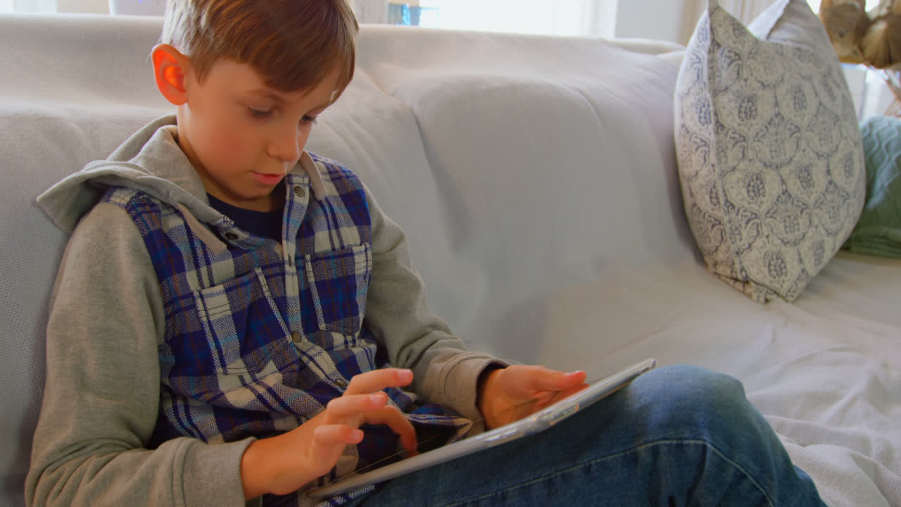 편안한 집에서 디지털 태블릿을 소송하는 백인 소년의 앞면 4k