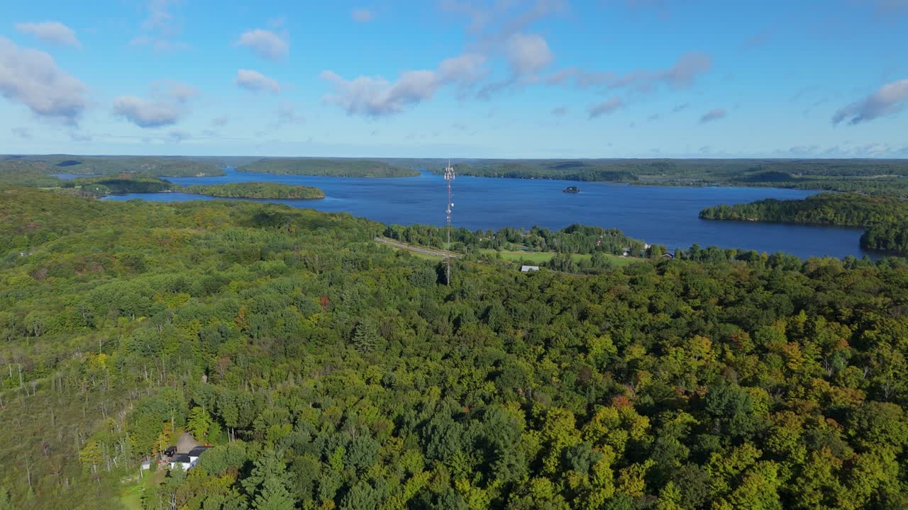 Aerial view of a lake surrounded by forest with a communications tower