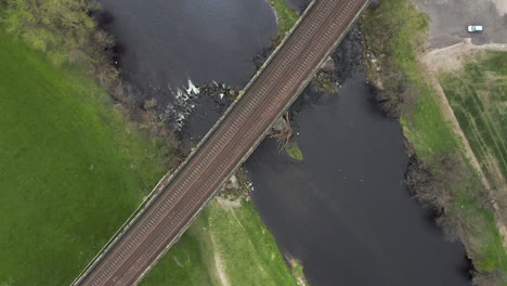 aerial birds eye view of train tracks crossing river in yorkshire, england with spiral reveal