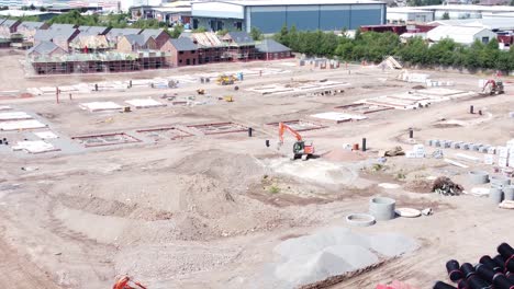 UK-town-housing-development-working-foundation-excavation-construction-site-aerial-view-slow-left-orbit-shot