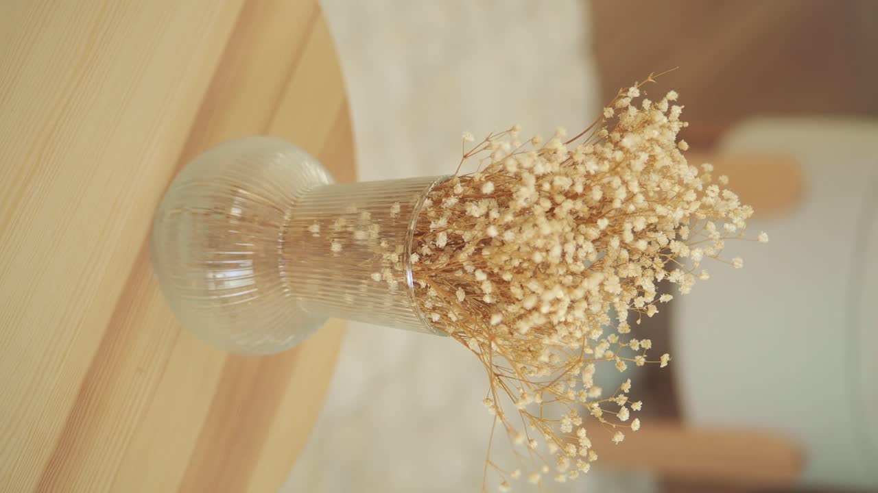 Close-up of hand arranging flowers in a vase on a wooden table