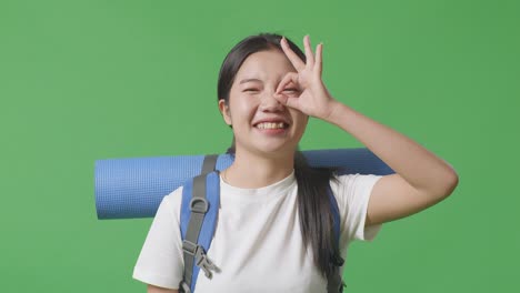 woman with backpack and yoga mat showing ok sign